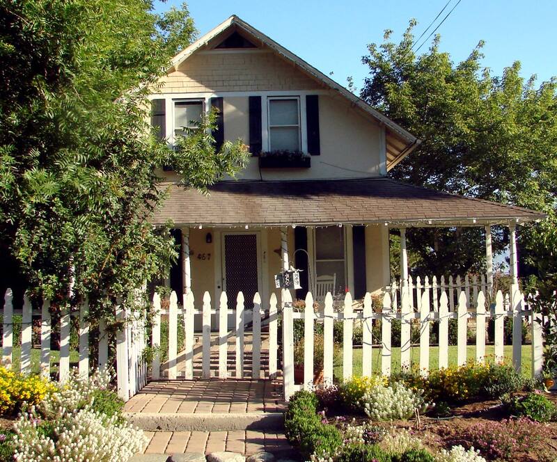 Cottage-style home with a white picket fence and flowering front garden