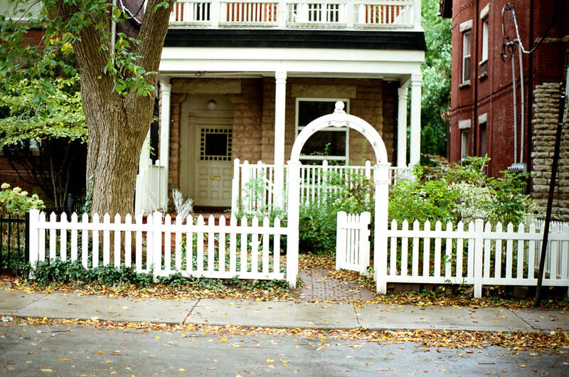 White timber picket fence with an arched garden gate in front of a home